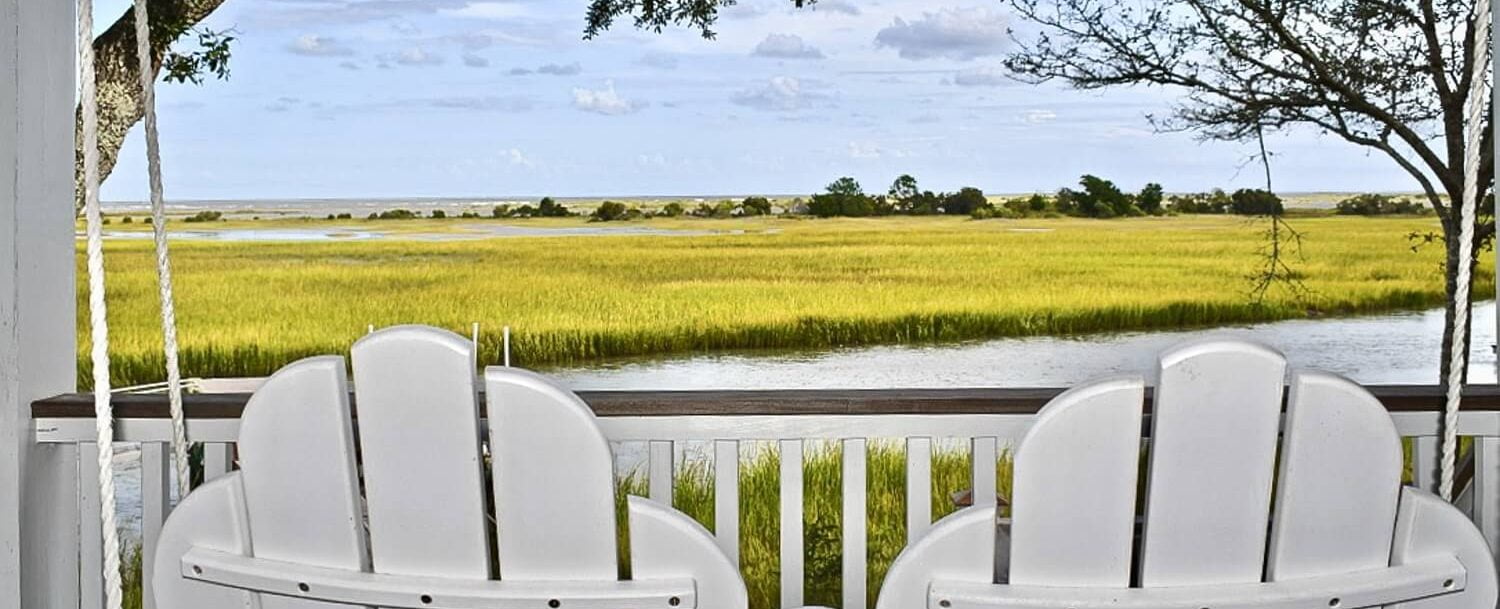 Wine Time - Backs of two white wood chairs in front of the marsh